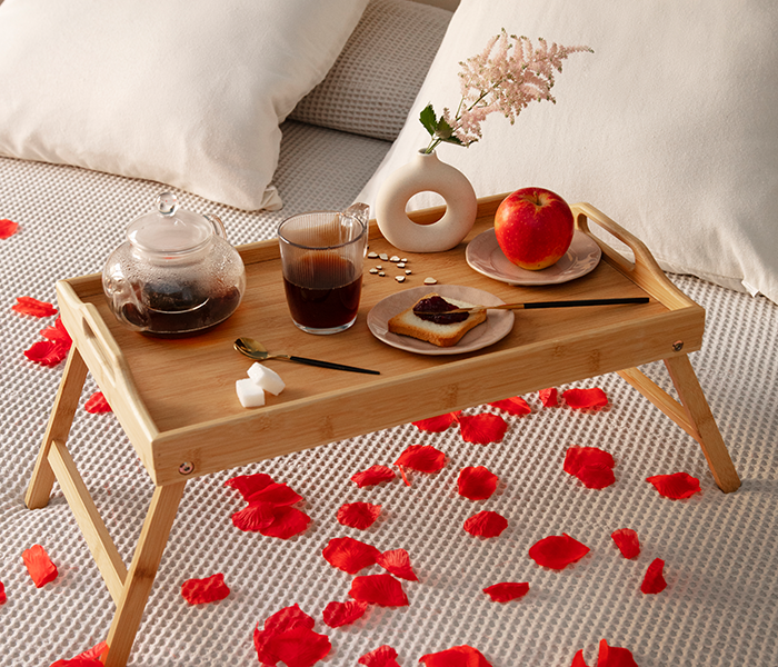 Breakfast tray on bed with rose petals